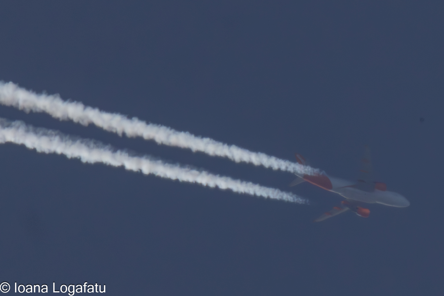 Jet flying across a clear blue sky, leaving trails